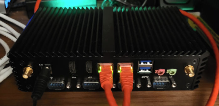 photo of a small fanless mini-pc amidst glowing lights and ethernet cables