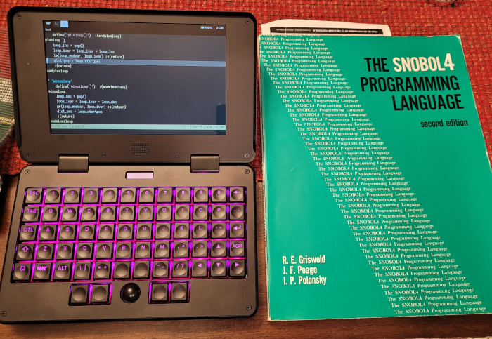 The green Snobol4 book by Griswold et al next to an MNT Pocket Reform laptop editing my Snobol4th interpreter