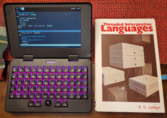 The Threaded Interpreted Languages book by Loeliger next to an MNT Pocket Reform laptop editing my snobol4th interpreter